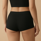 Person wearing black ribbed shorts on a beige background