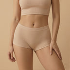 Person wearing beige ribbed tank top and high-waisted shorts on a beige background