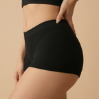 Person wearing black high-waisted shorts on a beige background