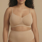 Woman wearing a beige bra and underwear set against a beige background