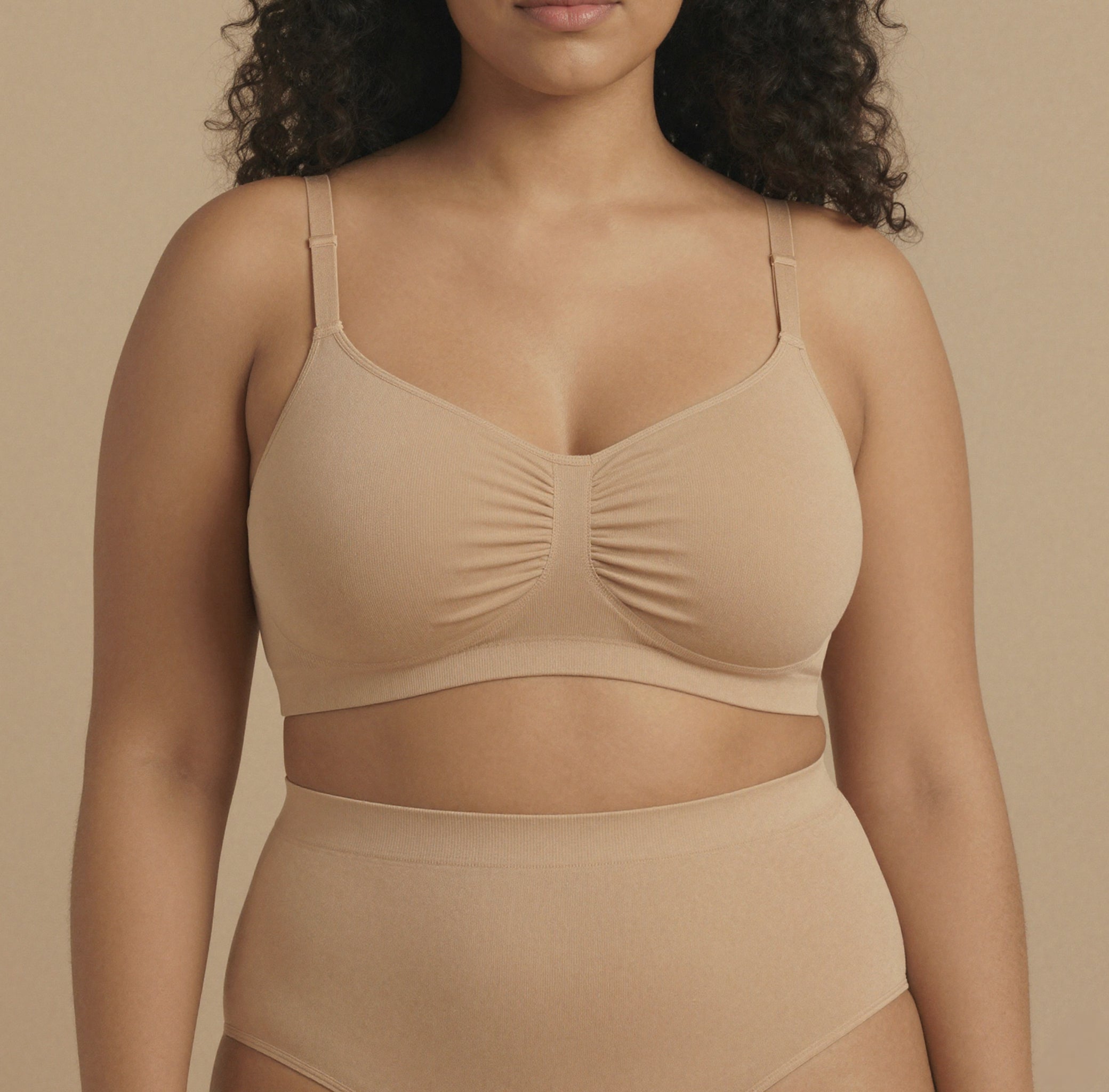 Woman wearing a beige bra and underwear set against a beige background