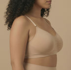 Woman wearing a beige bralette against a beige background