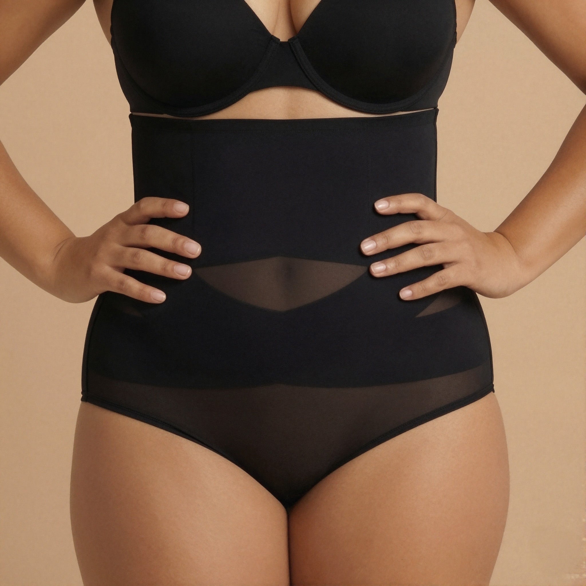 Person wearing a black shapewear garment on a beige background