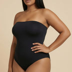 Woman wearing a black strapless swimsuit against a beige background
