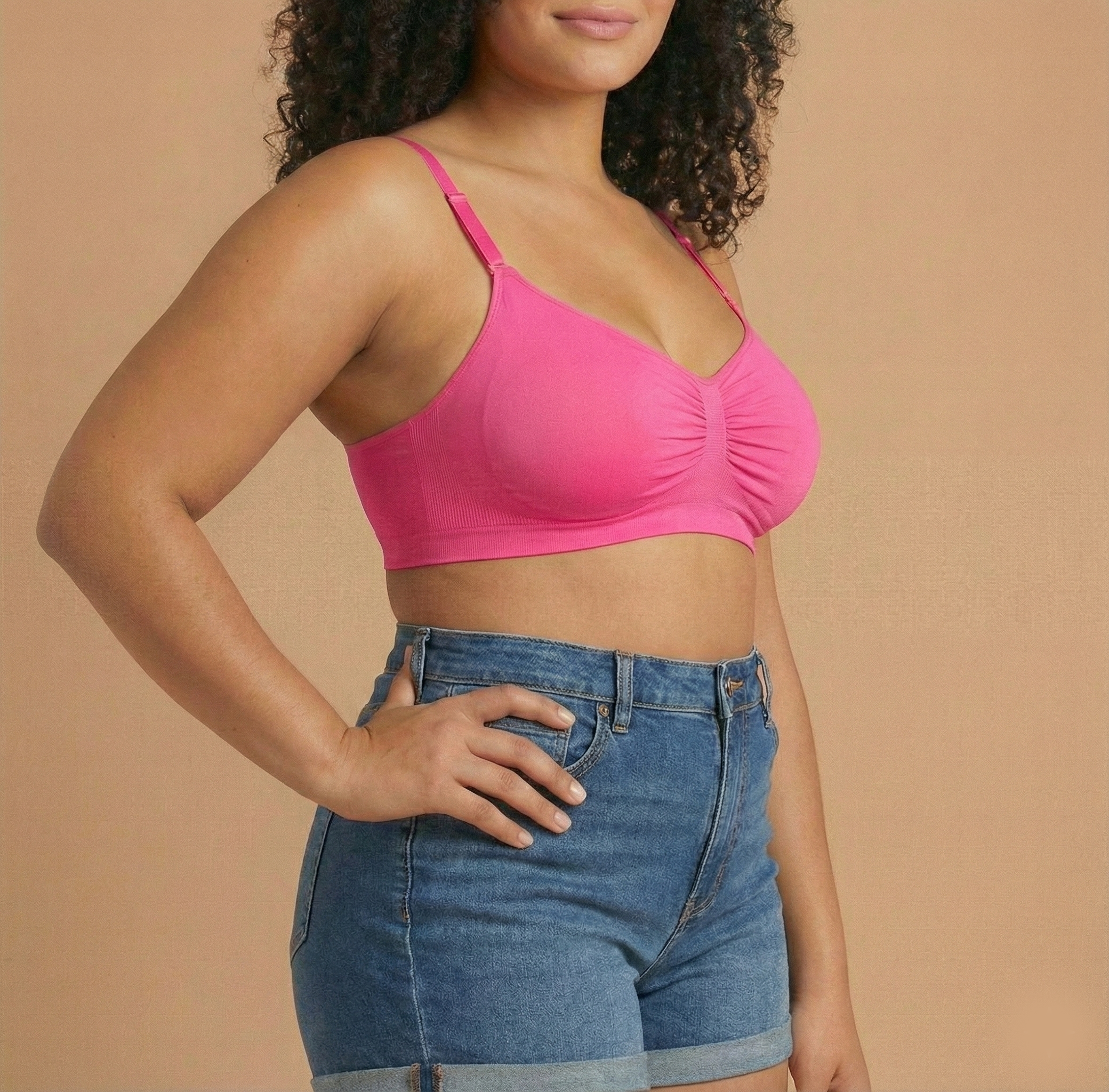 Woman wearing a pink crop top and blue shorts against a beige background